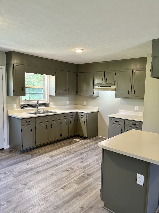 kitchen with light hardwood / wood-style floors, kitchen peninsula, and sink