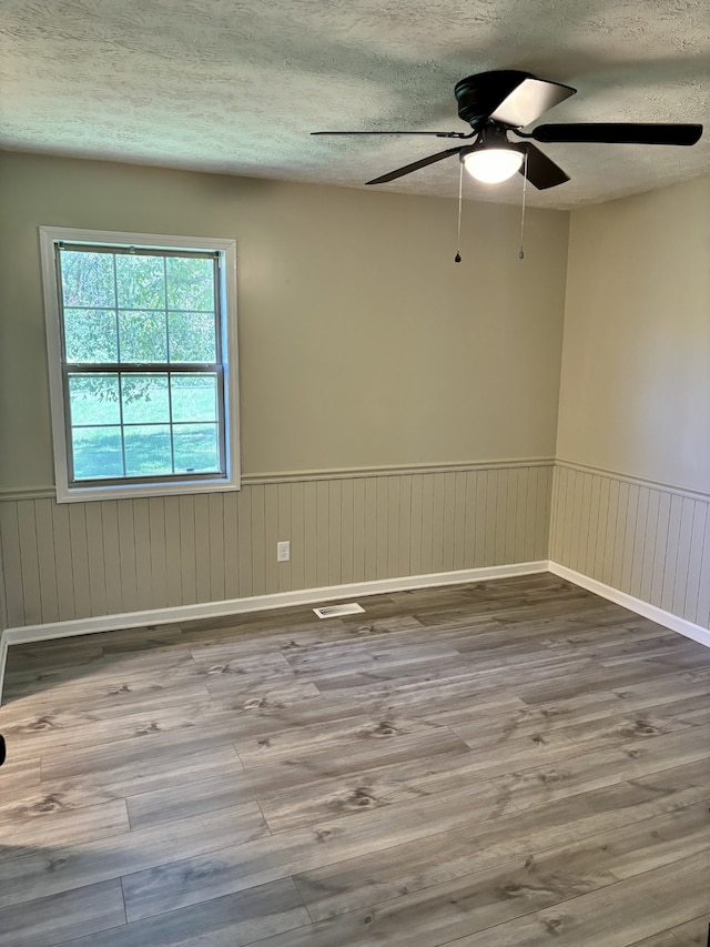 unfurnished room with a textured ceiling, wood-type flooring, and ceiling fan