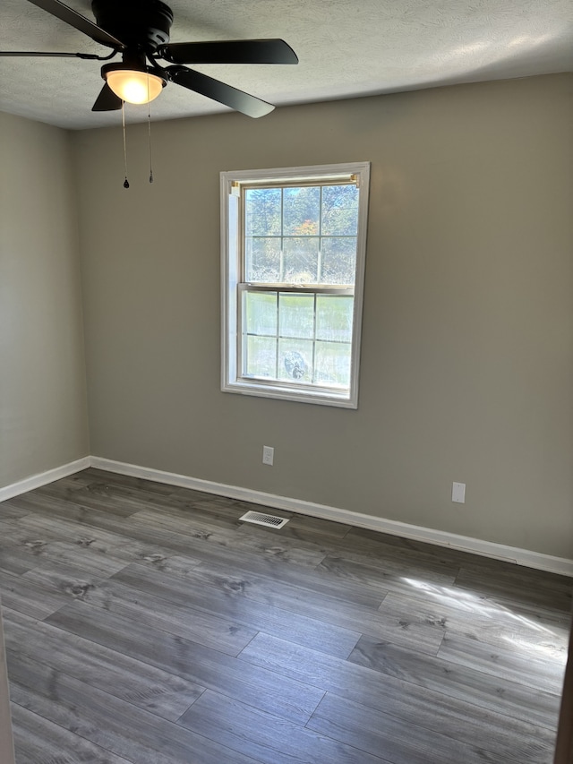 empty room with ceiling fan, a textured ceiling, and hardwood / wood-style floors