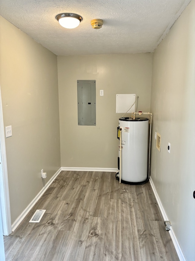 washroom featuring water heater, hookup for an electric dryer, electric panel, a textured ceiling, and light hardwood / wood-style floors