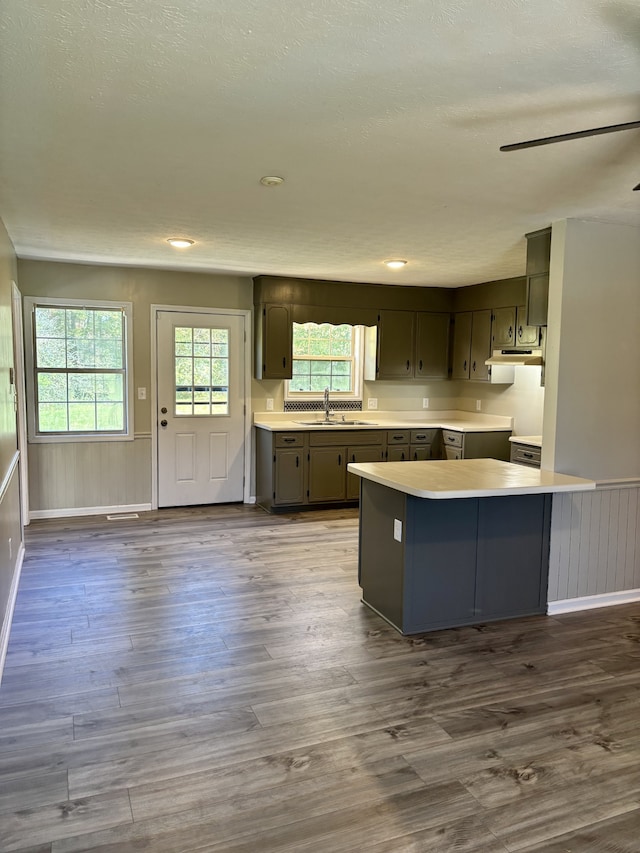 kitchen featuring kitchen peninsula, dark hardwood / wood-style flooring, a kitchen bar, gray cabinetry, and sink