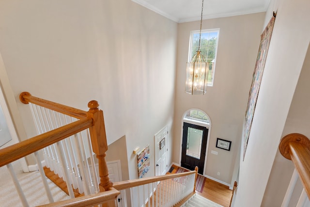 entrance foyer with light hardwood / wood-style floors, crown molding, a towering ceiling, and an inviting chandelier