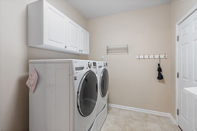 washroom featuring cabinets, washing machine and dryer, and light tile patterned floors