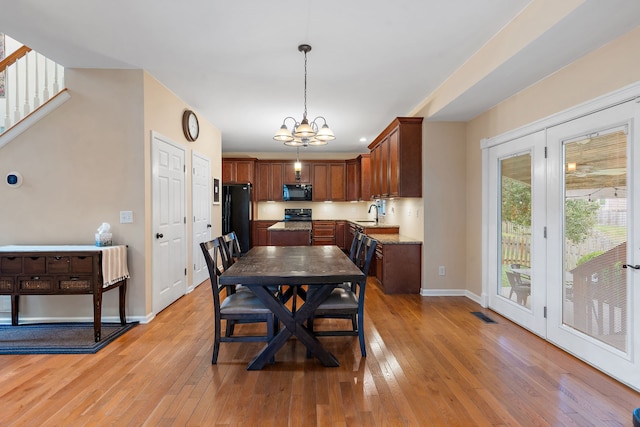 dining room featuring sink, an inviting chandelier, and light wood-type flooring