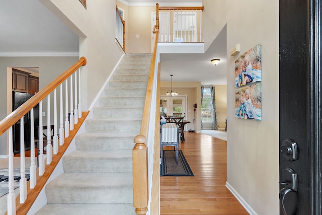 entryway featuring light hardwood / wood-style floors, ornamental molding, and a chandelier