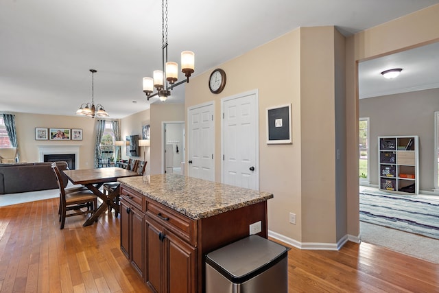 kitchen featuring light stone countertops, a kitchen island, hardwood / wood-style floors, pendant lighting, and a chandelier