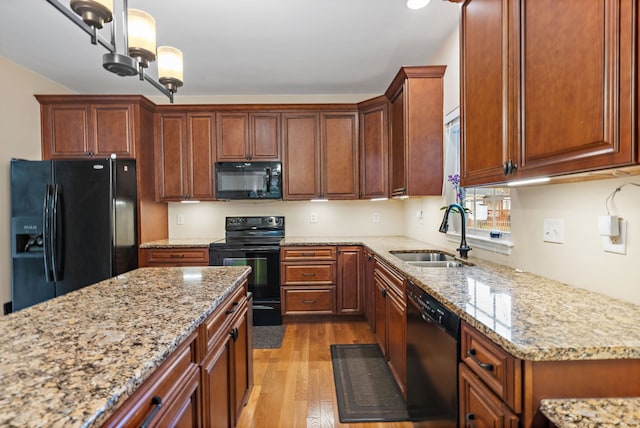 kitchen featuring light stone countertops, black appliances, sink, light hardwood / wood-style floors, and a chandelier