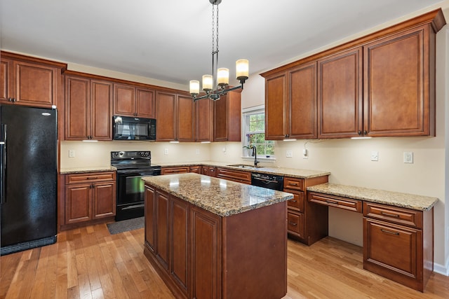 kitchen with light hardwood / wood-style flooring, hanging light fixtures, black appliances, a center island, and a notable chandelier