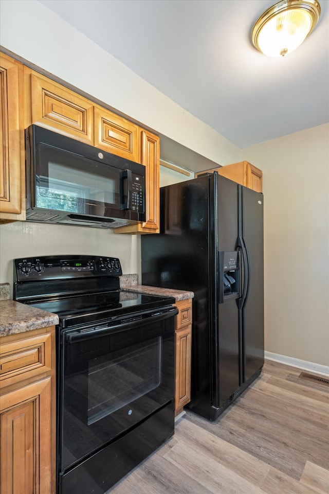 kitchen with black appliances and light hardwood / wood-style flooring