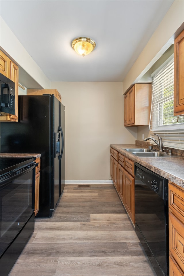 kitchen featuring black appliances, sink, and light wood-type flooring