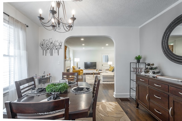 dining room featuring crown molding, a notable chandelier, a textured ceiling, and dark hardwood / wood-style flooring