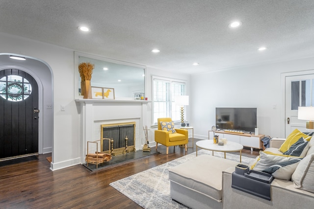 living room with a textured ceiling and dark hardwood / wood-style floors