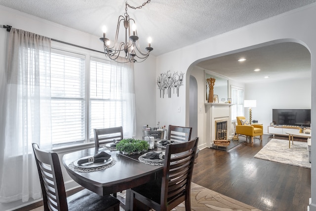 dining area with an inviting chandelier, crown molding, a textured ceiling, and dark hardwood / wood-style floors