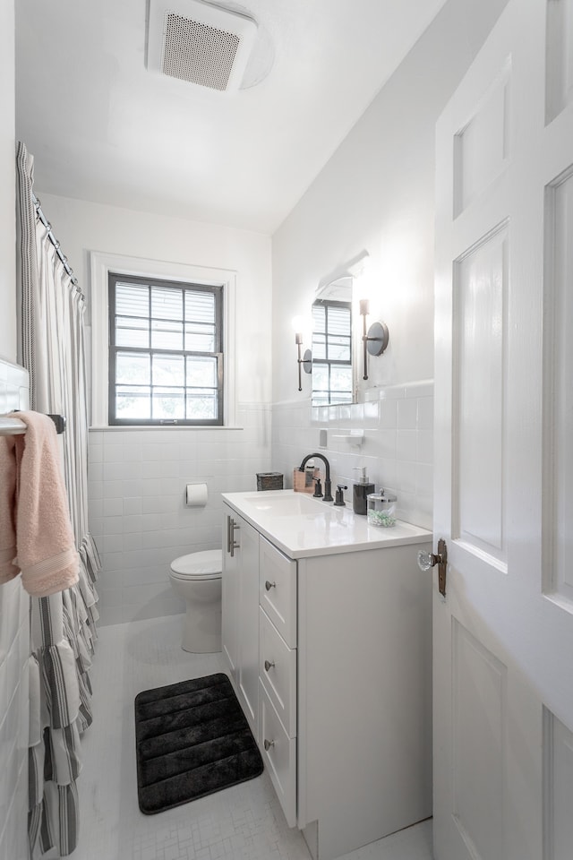 bathroom featuring tile walls, vanity, toilet, and plenty of natural light