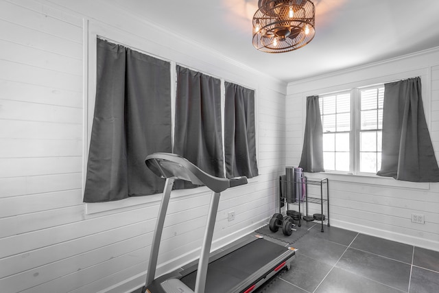 workout area featuring crown molding, wood walls, and dark tile patterned flooring