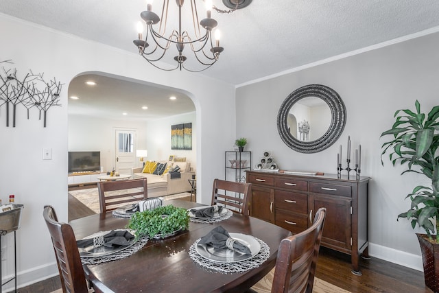 dining area with ornamental molding, a textured ceiling, dark hardwood / wood-style floors, and a chandelier