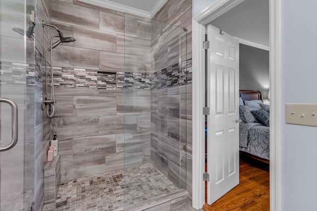 bathroom featuring ornamental molding, a shower with shower door, and hardwood / wood-style flooring