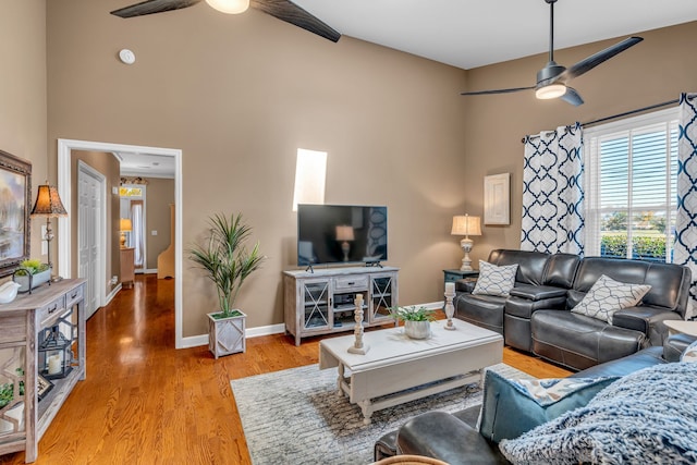 living room featuring light hardwood / wood-style floors, a high ceiling, and ceiling fan