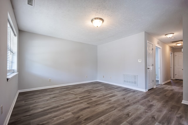 empty room with a textured ceiling and dark hardwood / wood-style flooring