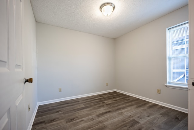 unfurnished room with dark wood-type flooring and a textured ceiling