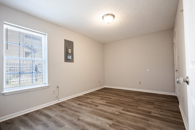 spare room featuring dark wood-type flooring, electric panel, and a textured ceiling