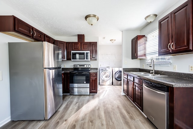 kitchen with a textured ceiling, sink, washing machine and dryer, light hardwood / wood-style floors, and stainless steel appliances