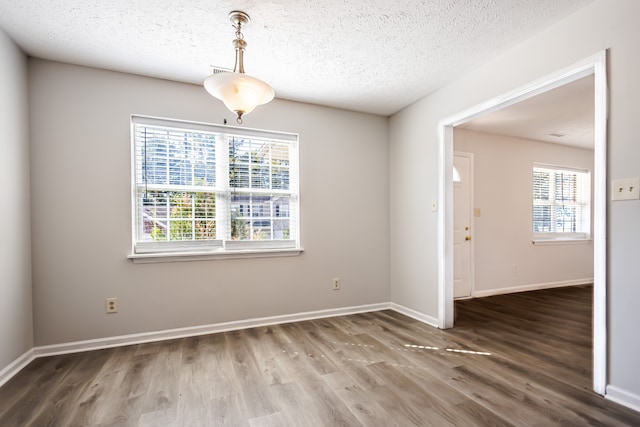 unfurnished room with a wealth of natural light, a textured ceiling, and hardwood / wood-style flooring