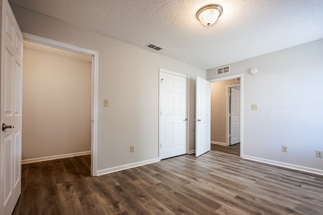 unfurnished bedroom with a closet, a textured ceiling, and dark hardwood / wood-style flooring