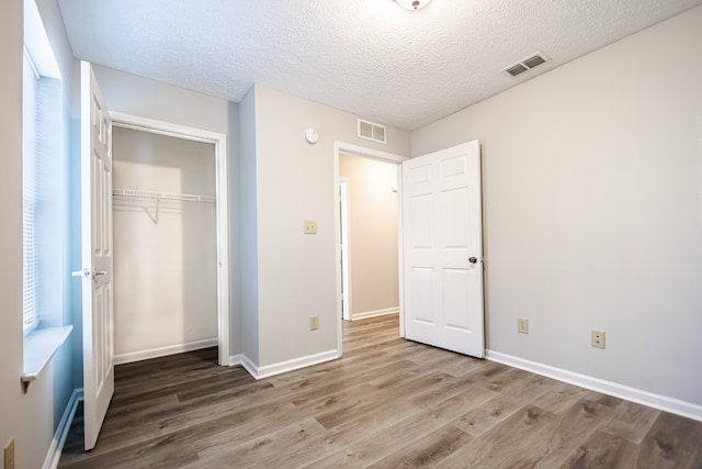 unfurnished bedroom featuring a closet, hardwood / wood-style floors, and multiple windows