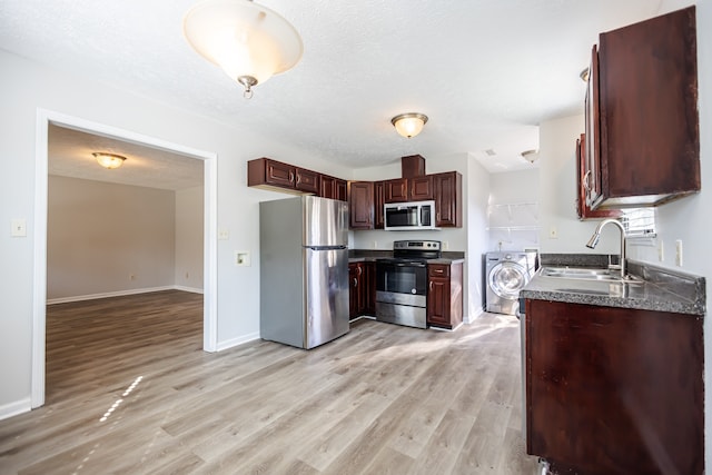 kitchen featuring washer / dryer, a textured ceiling, stainless steel appliances, and light hardwood / wood-style floors