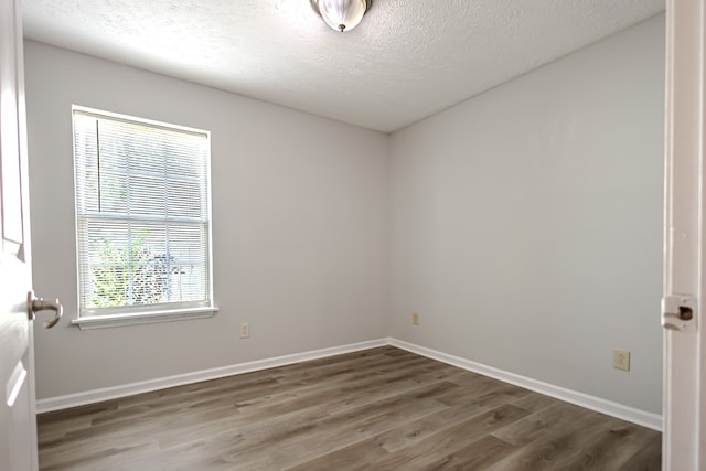 empty room with a textured ceiling and dark hardwood / wood-style flooring