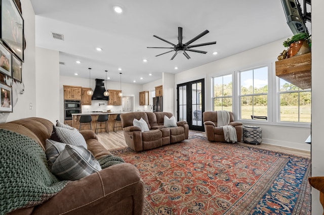 living room featuring french doors, light wood-type flooring, and ceiling fan