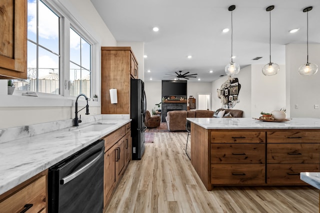 kitchen featuring dishwashing machine, brown cabinets, freestanding refrigerator, a sink, and open floor plan