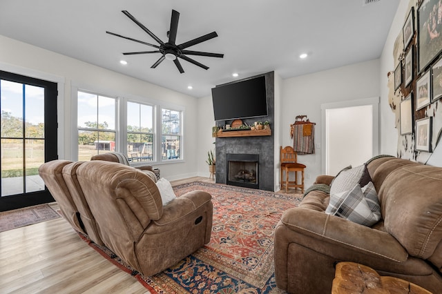 living room featuring a fireplace, light hardwood / wood-style floors, and ceiling fan