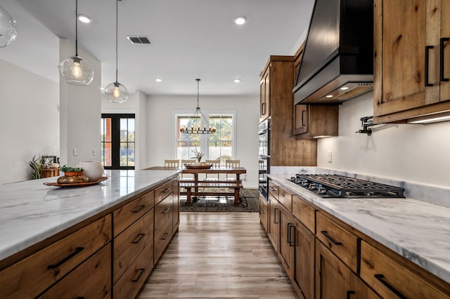 kitchen featuring custom exhaust hood, light wood-style flooring, gas stovetop, hanging light fixtures, and french doors