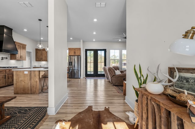 kitchen with light wood-type flooring, french doors, stainless steel fridge, ceiling fan, and pendant lighting