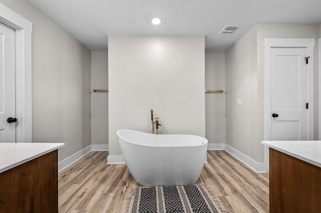 full bathroom featuring visible vents, a freestanding bath, wood finished floors, and vanity