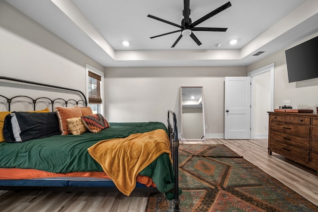 bedroom featuring visible vents, baseboards, recessed lighting, wood finished floors, and a raised ceiling