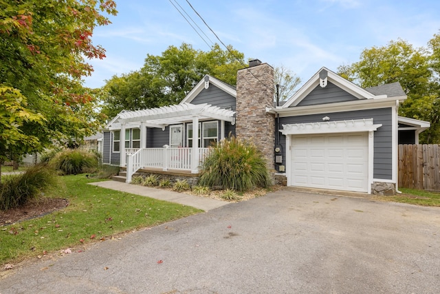 view of front of house featuring covered porch, a front yard, and a garage