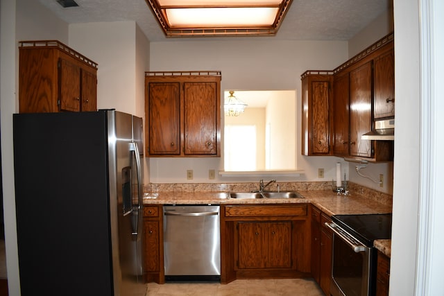 kitchen with sink, a textured ceiling, stainless steel appliances, light stone counters, and extractor fan