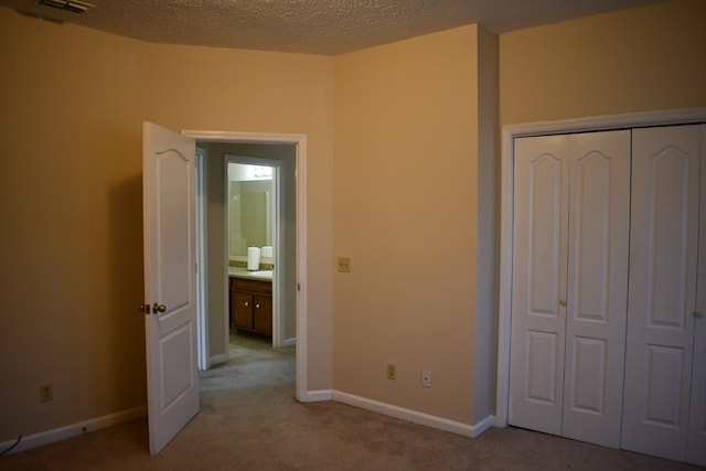 unfurnished bedroom with a closet, light carpet, and a textured ceiling