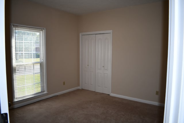 unfurnished bedroom with a closet and dark carpet