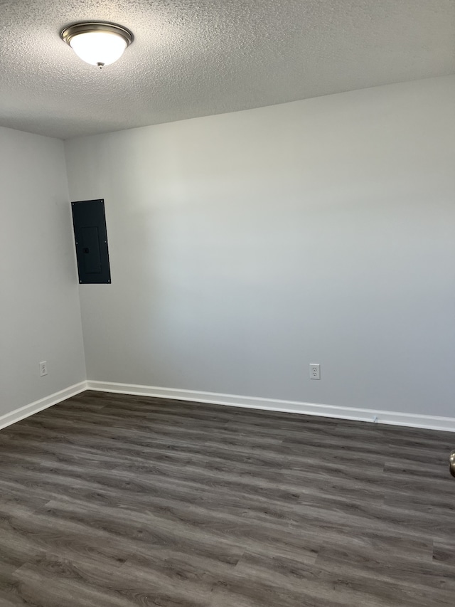 spare room with electric panel, dark wood-type flooring, and a textured ceiling