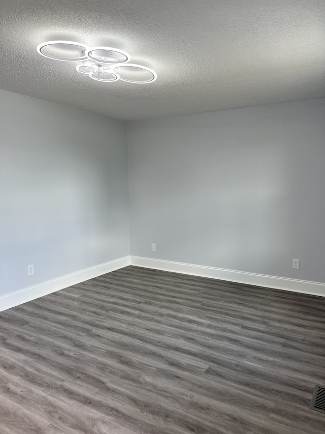 spare room with a textured ceiling and dark hardwood / wood-style flooring