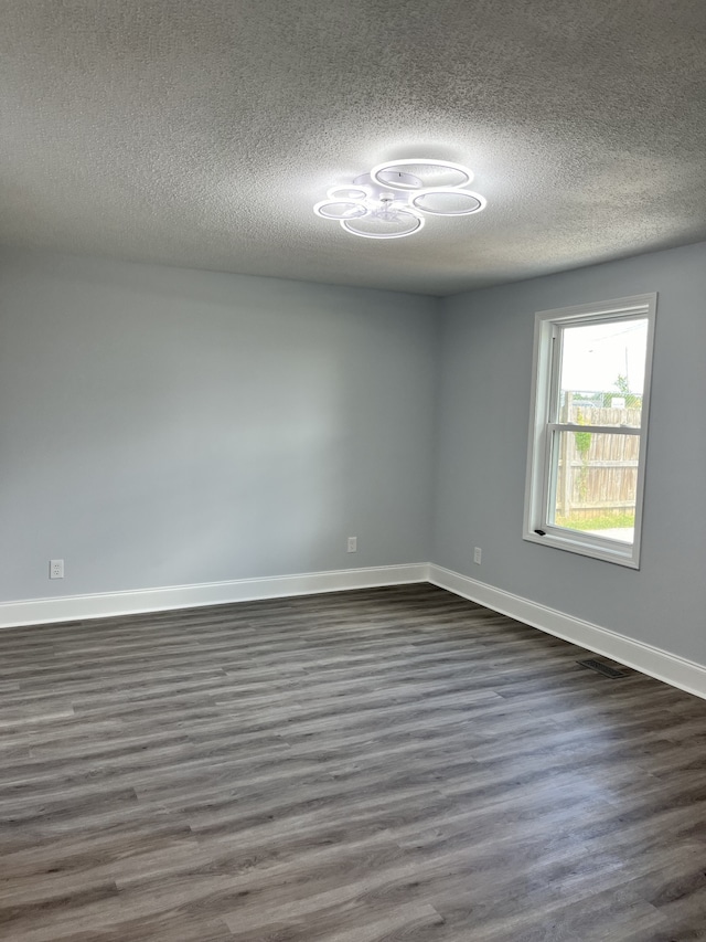 unfurnished room with dark wood-type flooring and a textured ceiling