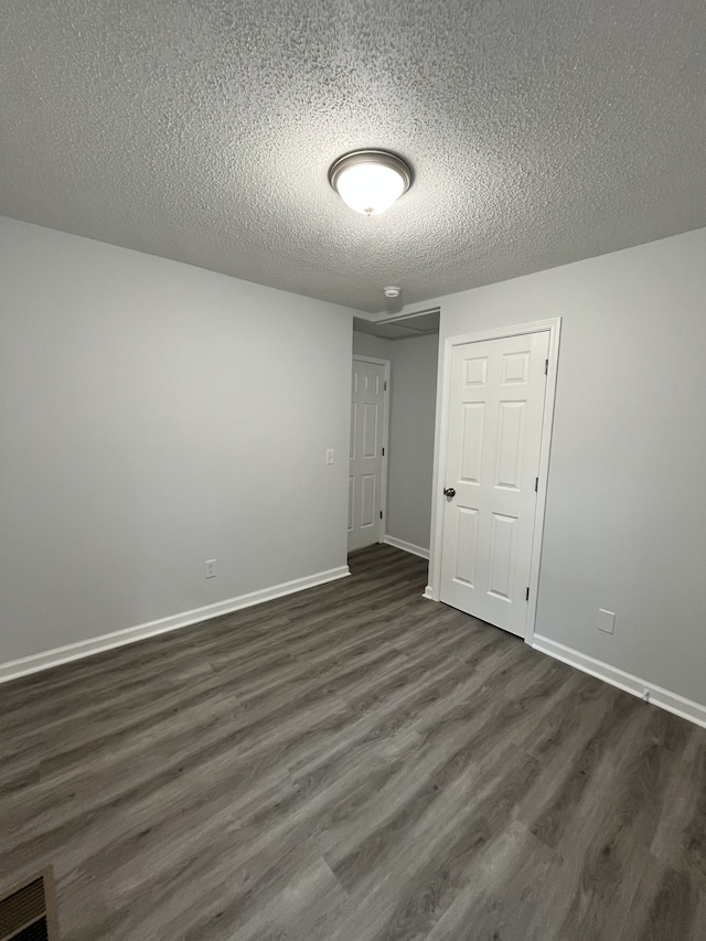 spare room with a textured ceiling and dark hardwood / wood-style flooring