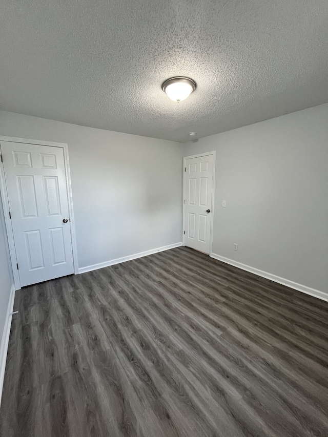 empty room featuring a textured ceiling and dark hardwood / wood-style flooring