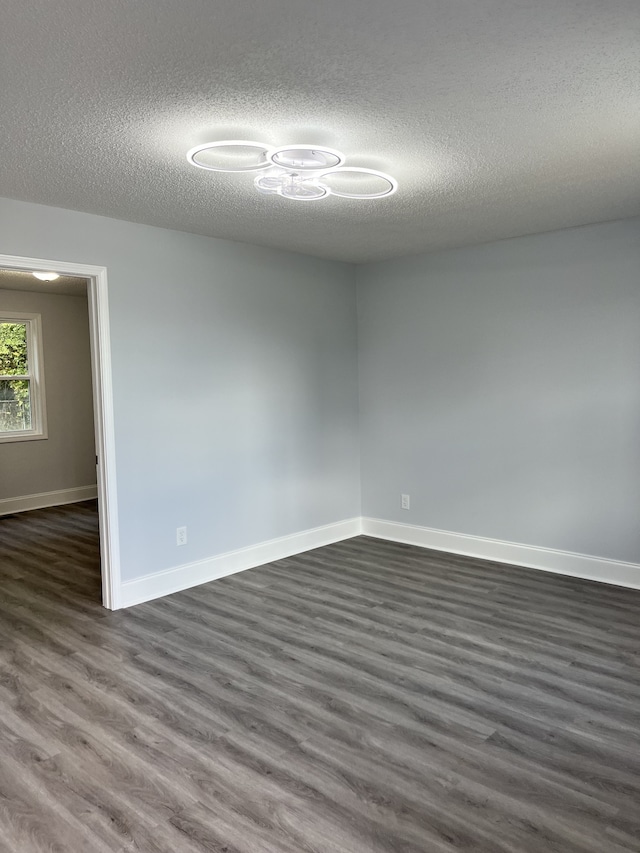 spare room featuring a textured ceiling and dark hardwood / wood-style floors