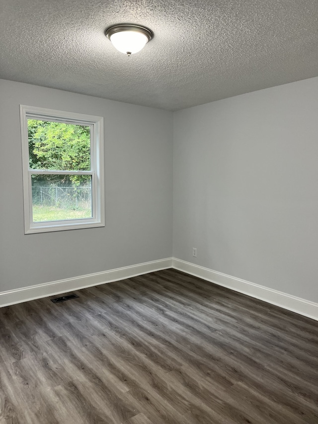 unfurnished room featuring a textured ceiling and dark hardwood / wood-style floors