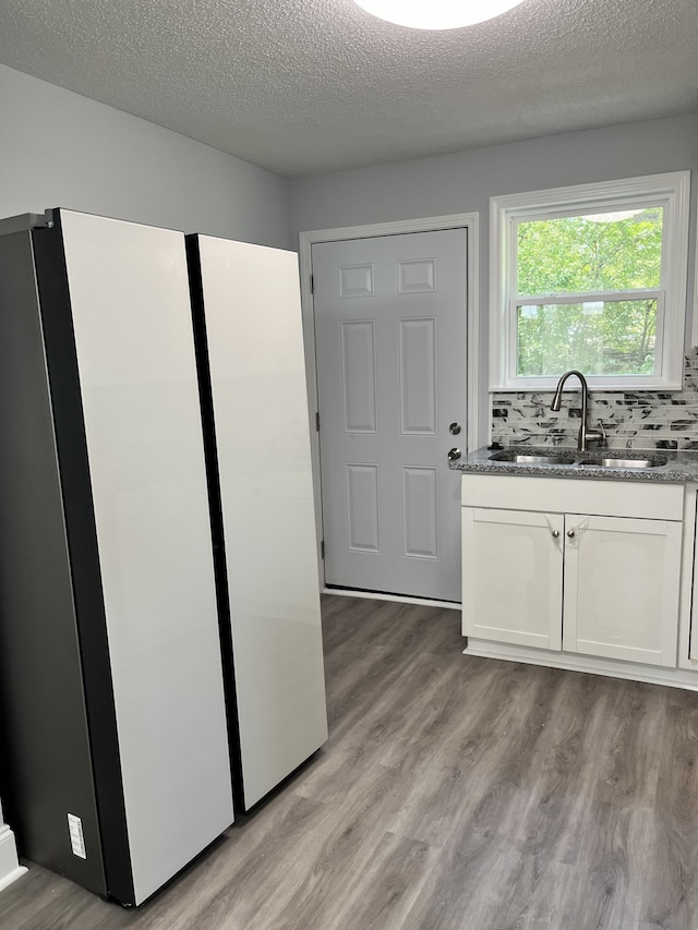 kitchen with decorative backsplash, fridge, light hardwood / wood-style flooring, sink, and white cabinetry